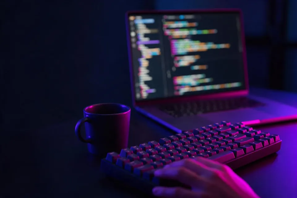 Laptop with blurred glowing lines on screen and a keyboard in a dark room