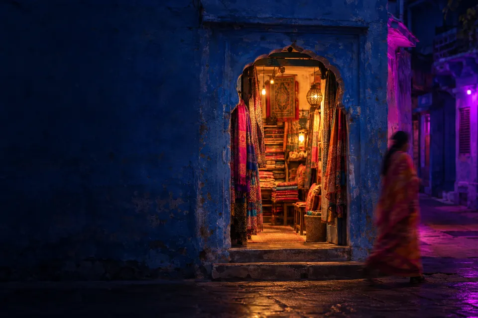 Textile shopfront on a blue-painted street at night